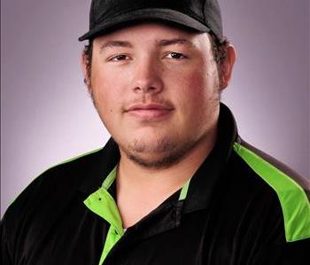Male with brown hair and a SERVPRO cap. Wearing black and green polo.